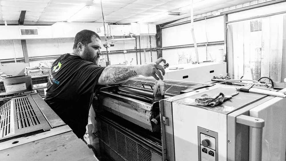 Man operating sheet-fed printing press