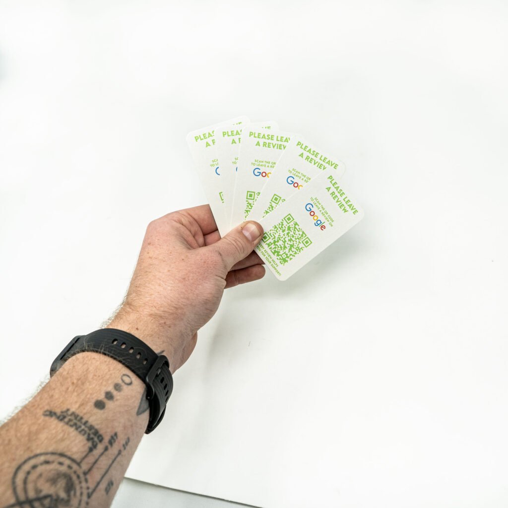 A hand holding multiple green review cards printed on business card paper stock with rounded corners.